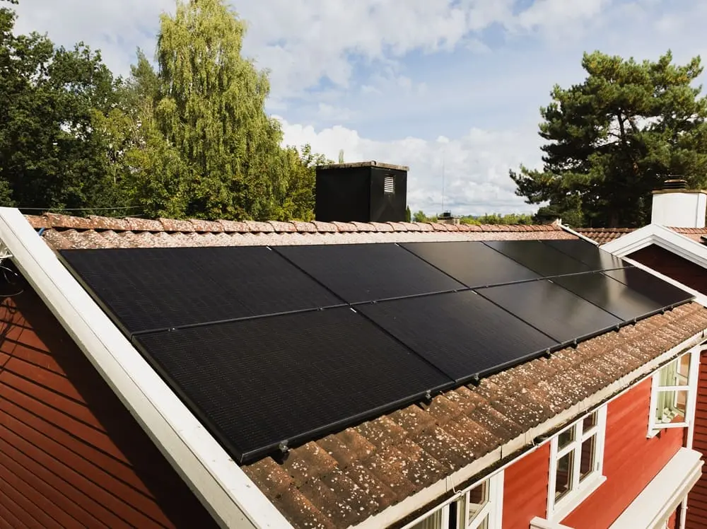 nærbilde av et rødt hus som har solcellepaneler på taket